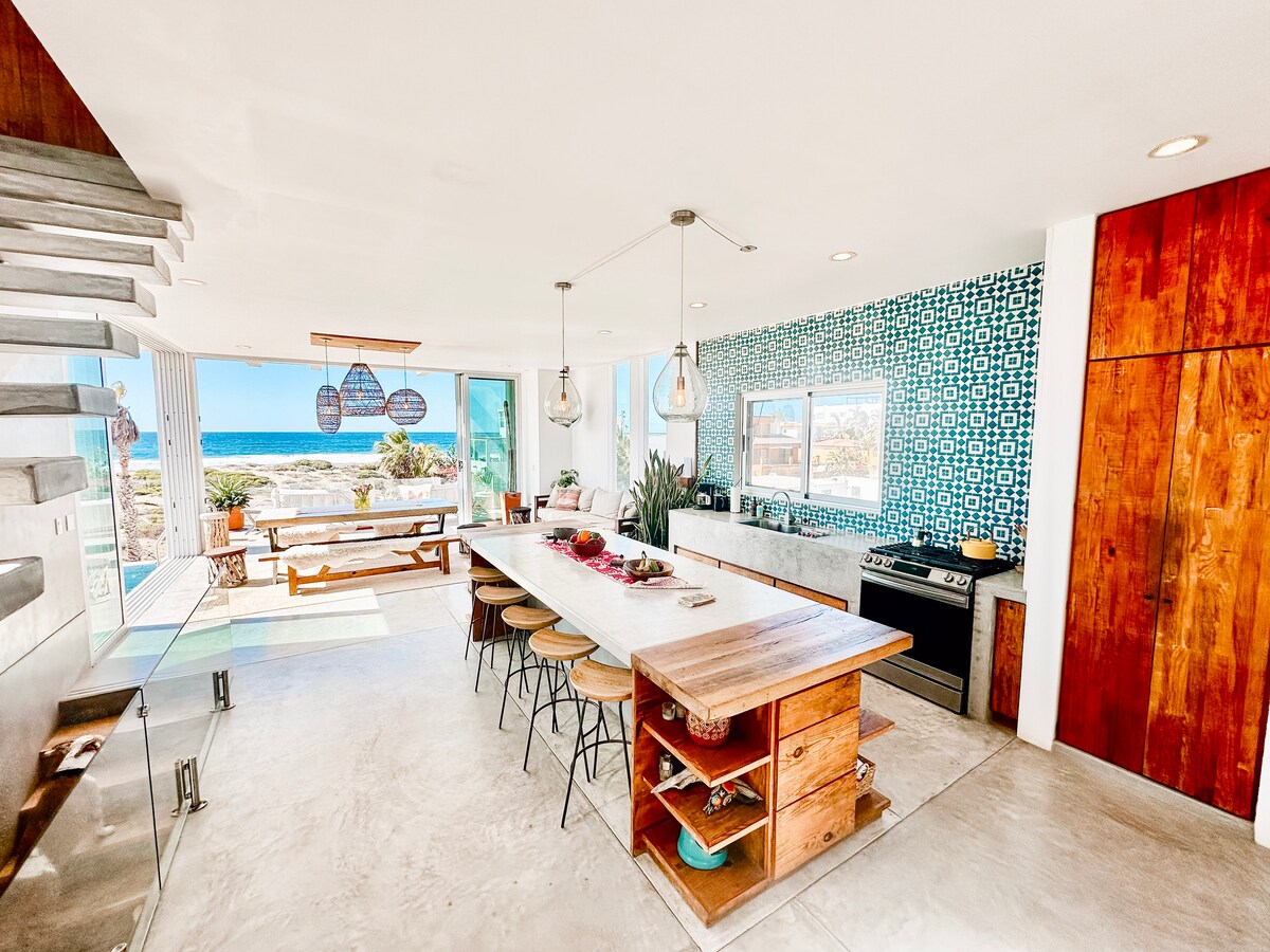 Open kitchen, dining and living room with the Pacific visible through folding glass doors