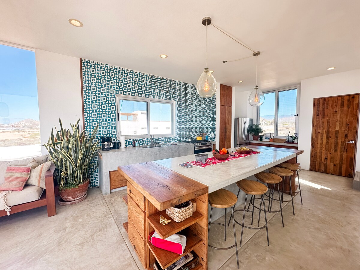 Kitchen island with seating beside the blue-and-white tiled cooking wall